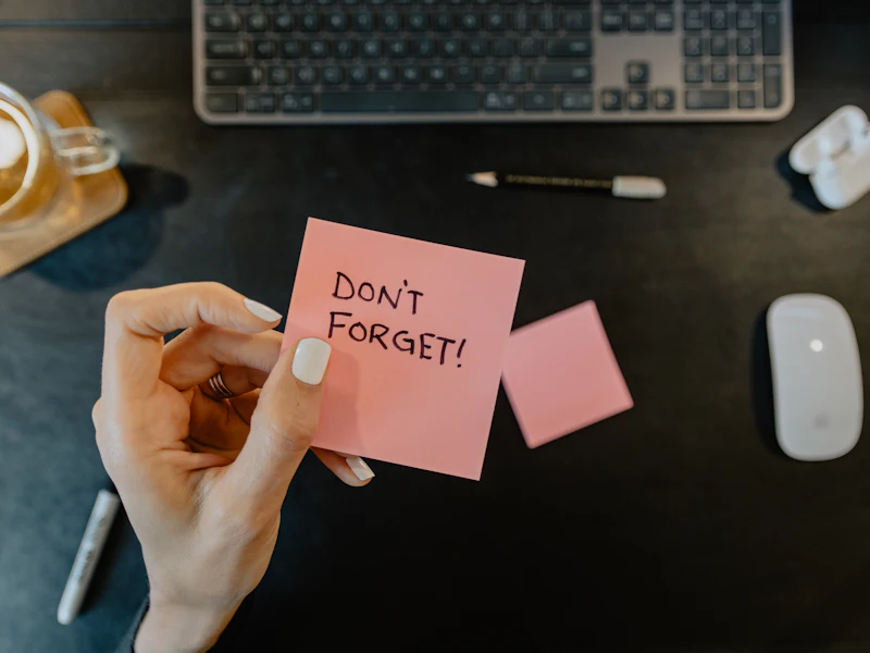 A hand holding a sticky note that says don&rsquo;t forget.